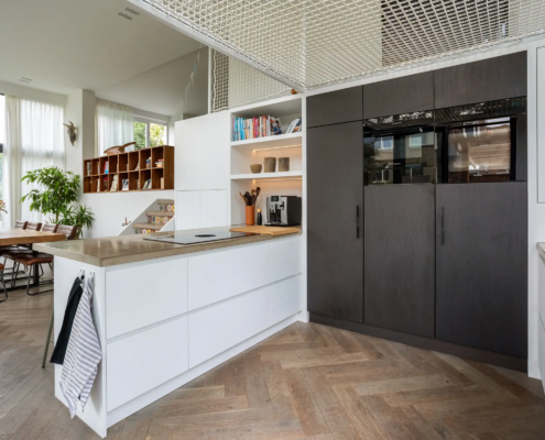 Keuken met wit eiland en zwarte, hoge kastenwand met oven