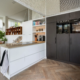 Keuken met wit eiland en zwarte, hoge kastenwand met oven